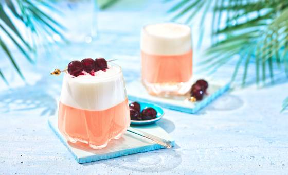 Two cherry sours in glasses garnished with 3 cherries.