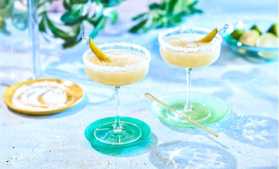 Pickle margarita on marble table top garnished with pickle slice